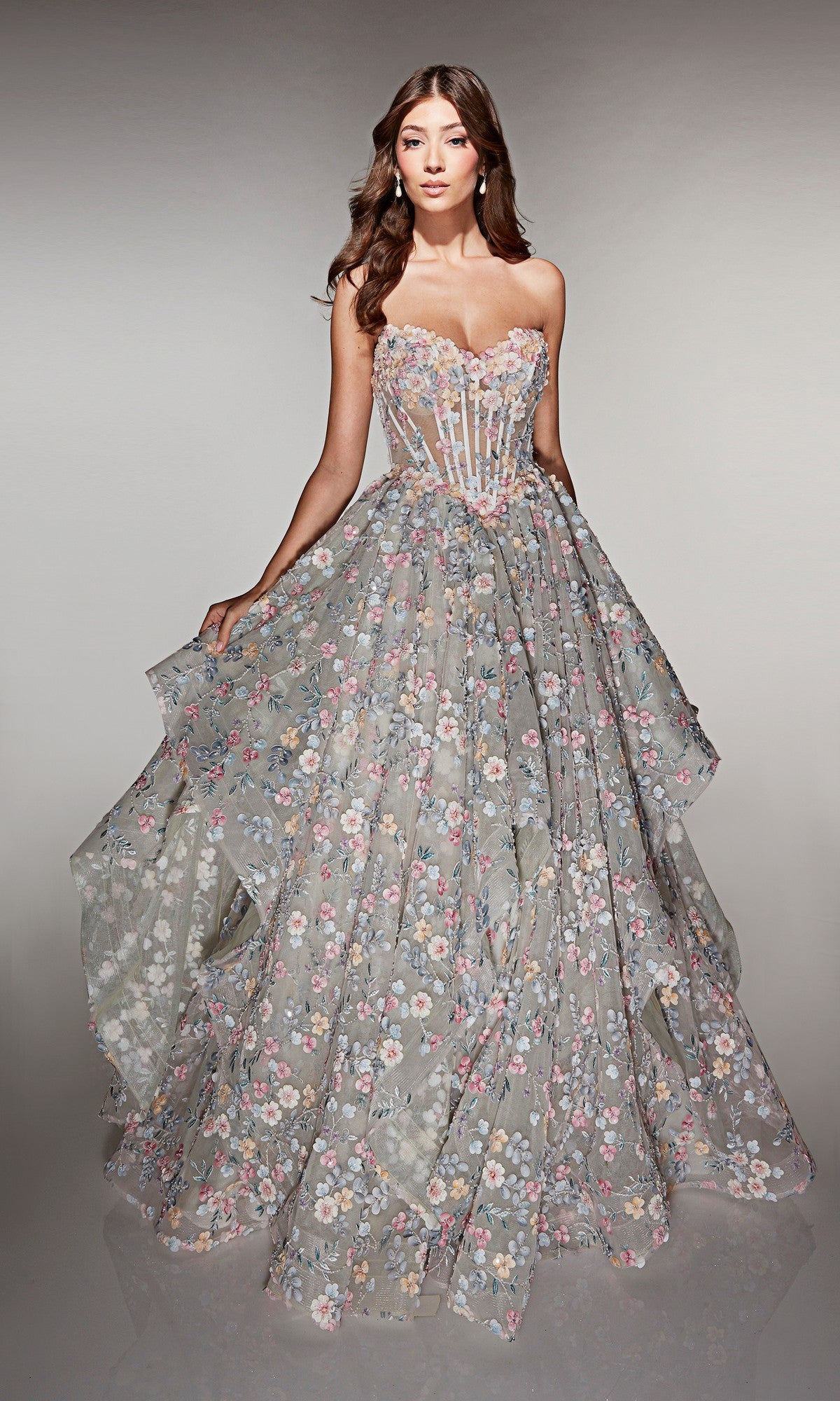 A woman wearing the Alyce 62048 long prom dress, featuring a strapless ball gown silhouette with a sheer corset bodice and intricate floral appliqué on the floor-length skirt.